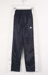 Black Adidas tracksuit pants hanging on a white background