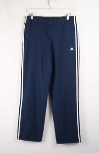 Navy blue Adidas tracksuit pants with white stripes on a white background
