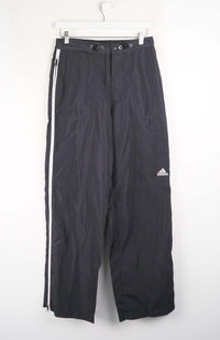 Black Adidas pants with white stripes on a white background