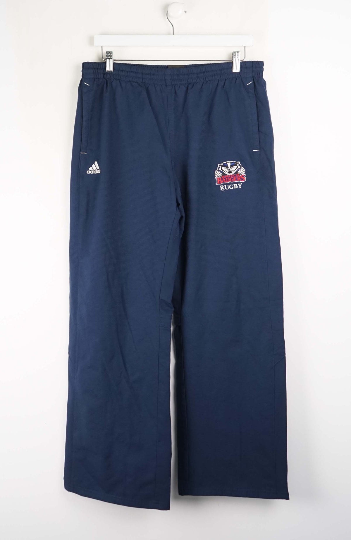 Navy blue rugby pants with a logo and Adidas branding on a white background