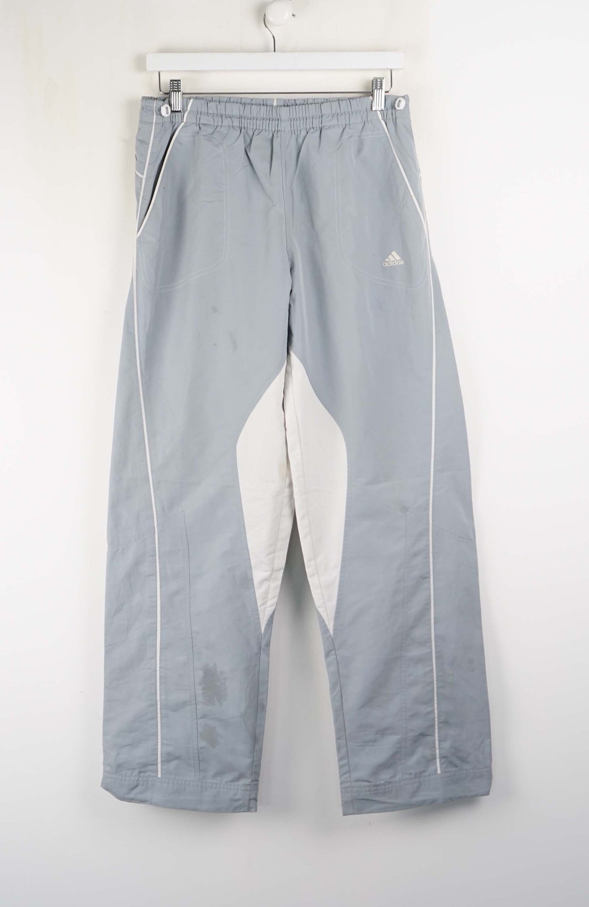 Gray pants with white accents hanging on a white wall