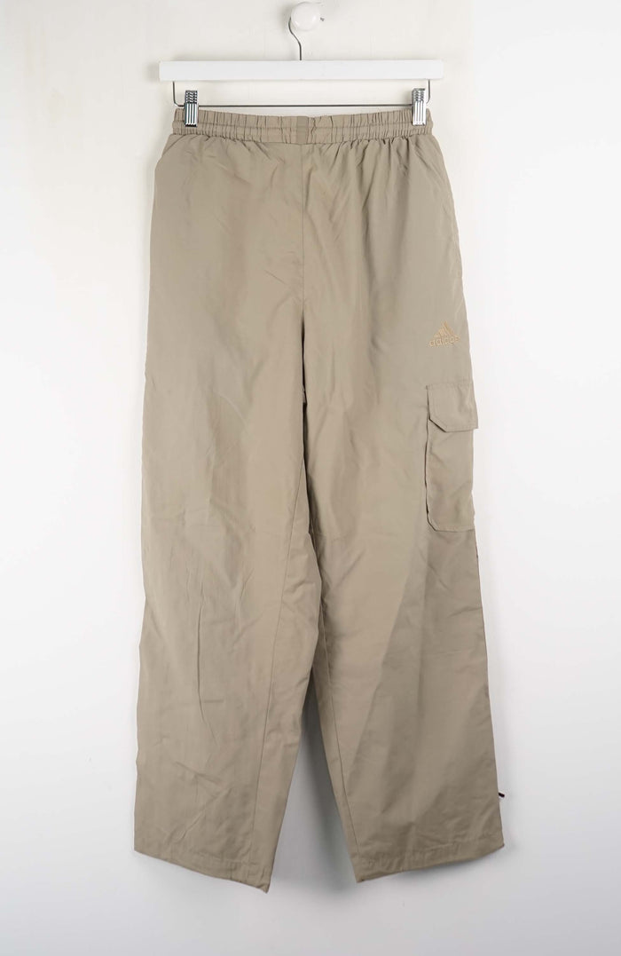 Beige pants hanging on a white rack against a white background