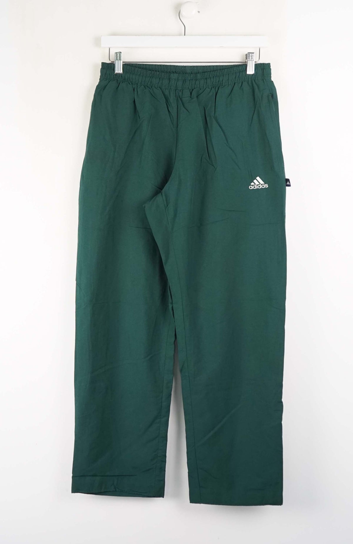 Green Adidas pants hanging on a white background