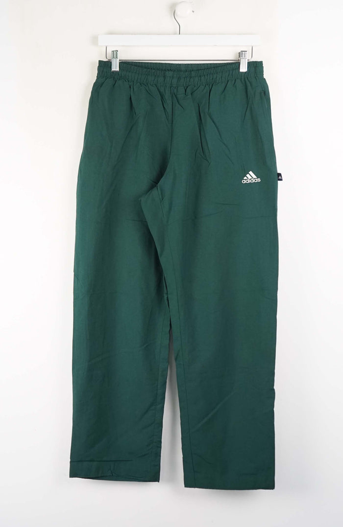 Green Adidas pants hanging on a white background