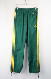 Green Adidas tracksuit pants with yellow stripes on a white background