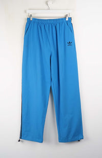 Blue Adidas pants hanging on a white background
