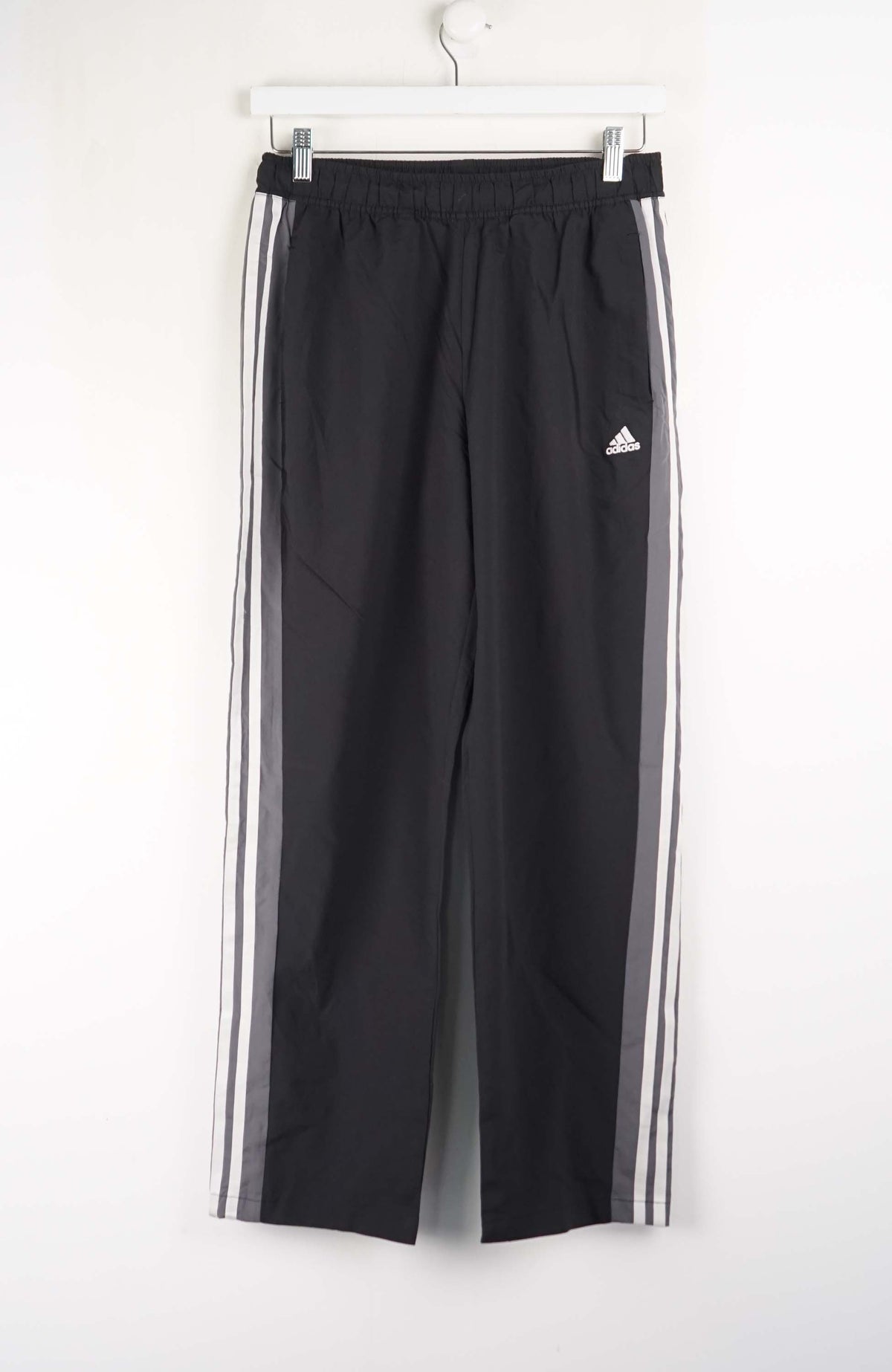 Black Adidas pants with white stripes on a white background