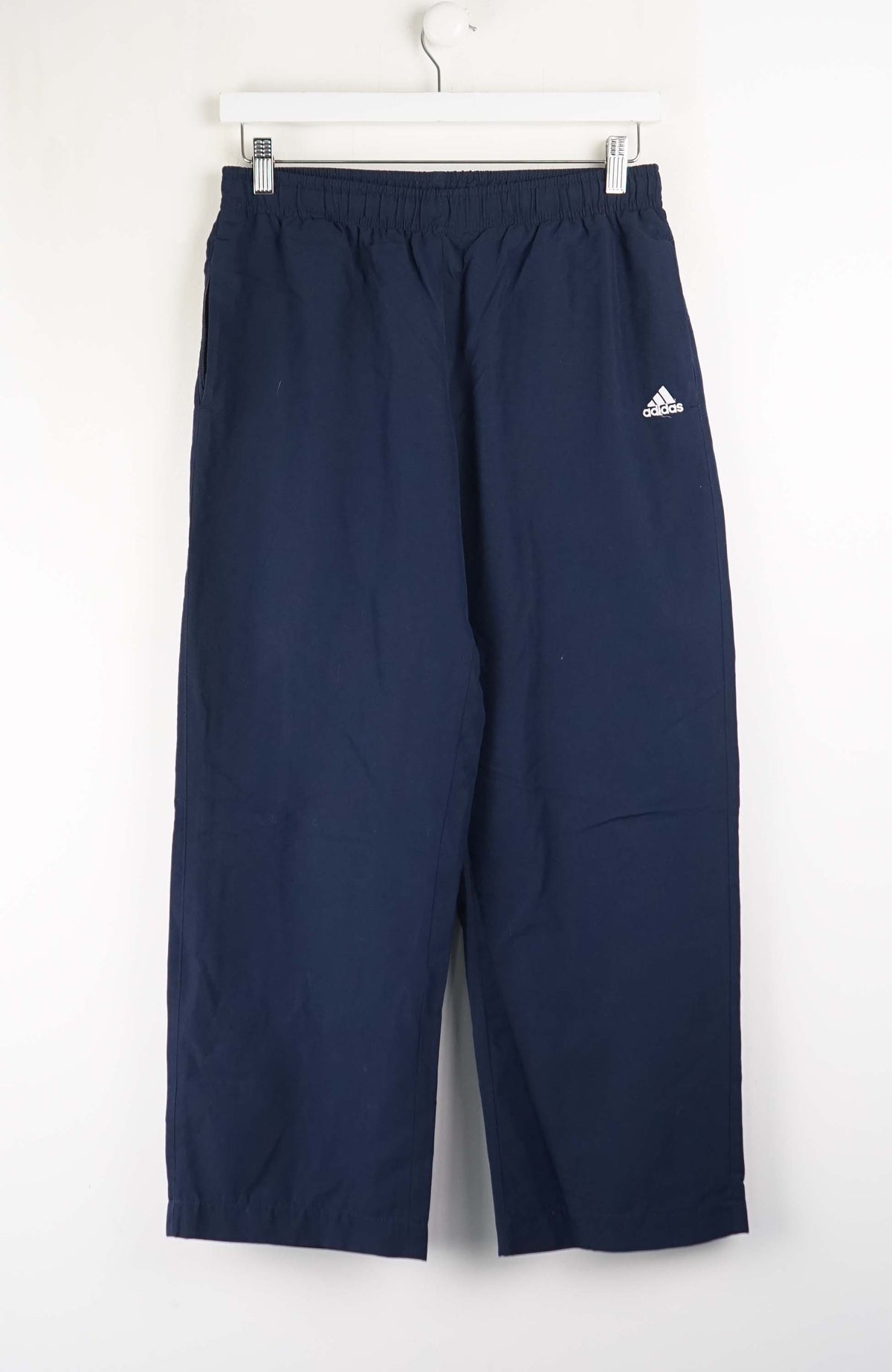 Navy blue Adidas pants on a white hanger against a white background