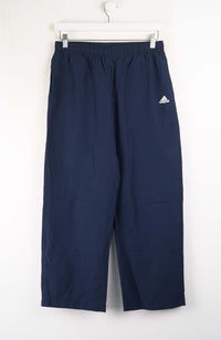 Navy blue Adidas pants on a white hanger against a white background
