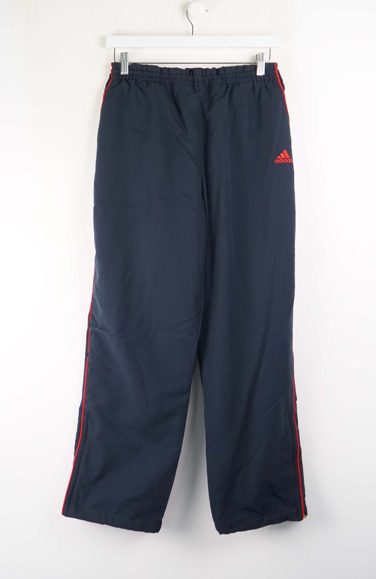 Navy blue pants with red stripes and Adidas logo on a white background