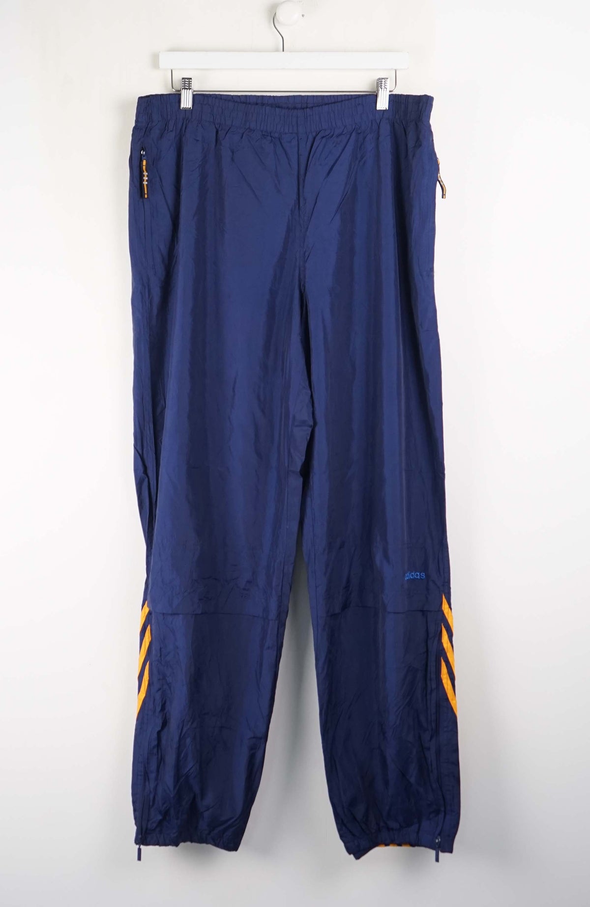 Blue pants with yellow accents hanging on a white background