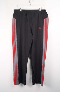 Black track pants with red and gray stripes on a white background