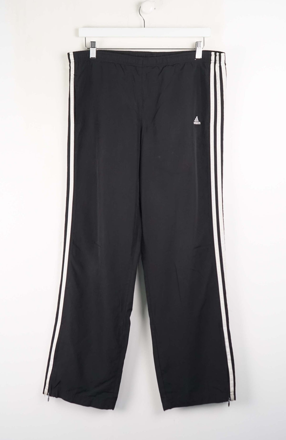 Black track pants with white stripes on a white background