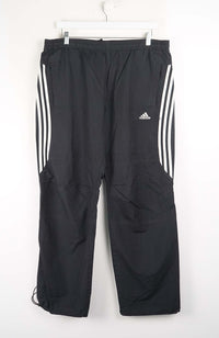 Black Adidas pants with three white stripes on a white background