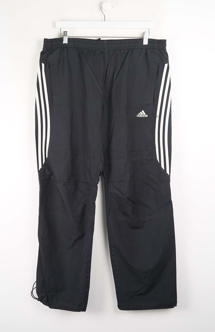 Black Adidas pants with three white stripes on a white background