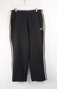 Black Adidas tracksuit pants with white stripes on a white background