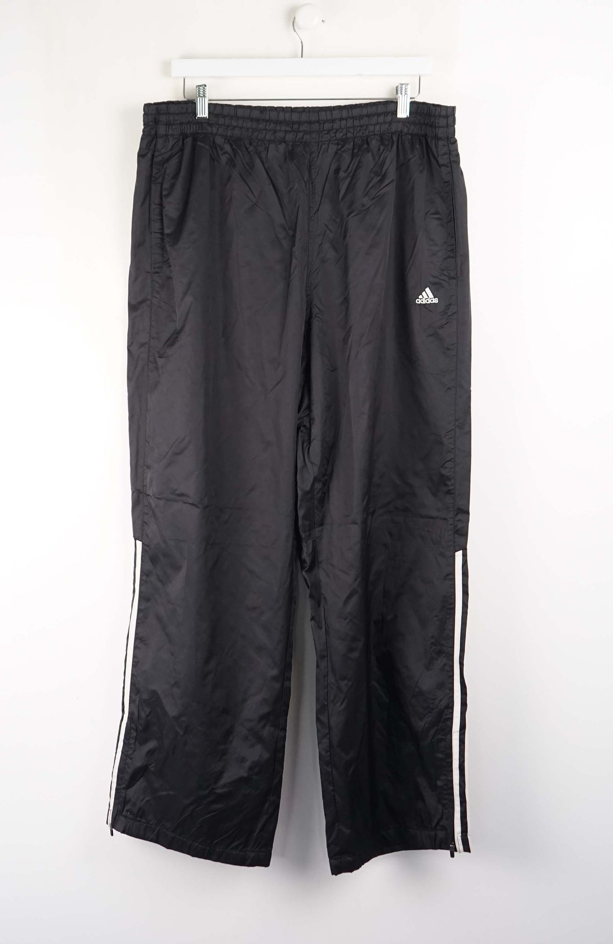Black Adidas tracksuit pants on a white background