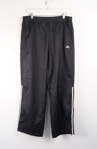 Black Adidas tracksuit pants on a white background
