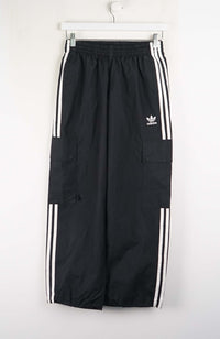 Black Adidas tracksuit pants with white stripes on a white background