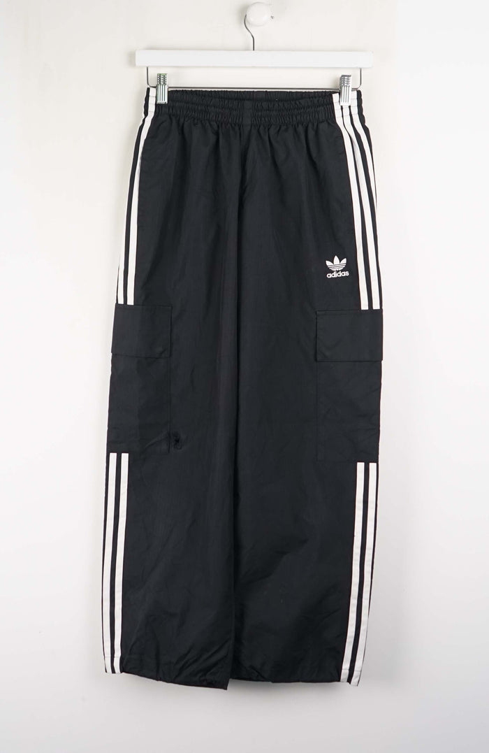 Black Adidas tracksuit pants with white stripes on a white background