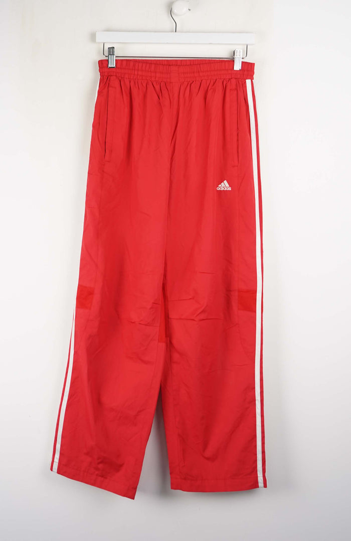 Red Adidas tracksuit pants with white stripes on a white background