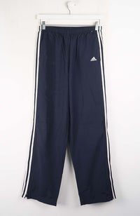 Navy blue Adidas tracksuit pants with white stripes on a white background