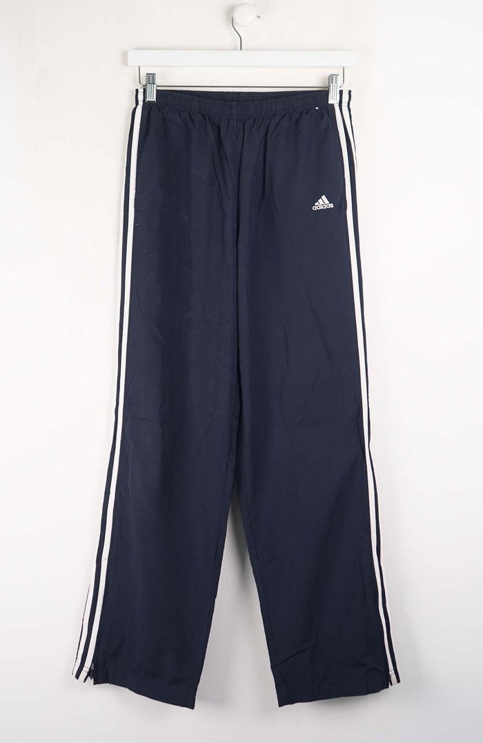Navy blue Adidas tracksuit pants with white stripes on a white background