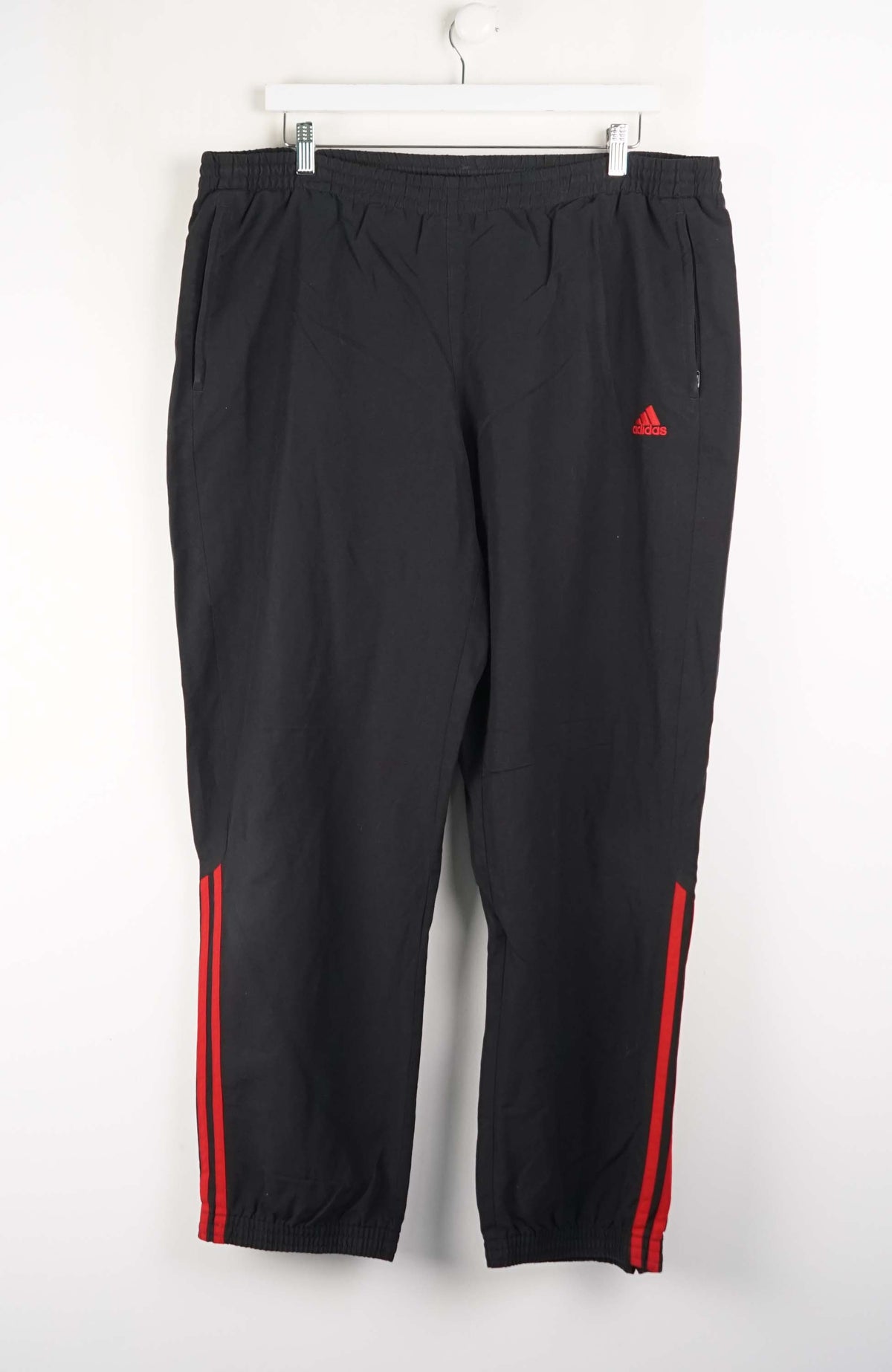Black pants with red stripes and a triangle logo on a white background