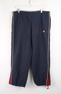 Navy blue tracksuit pants with red and white stripes hanging on a white background