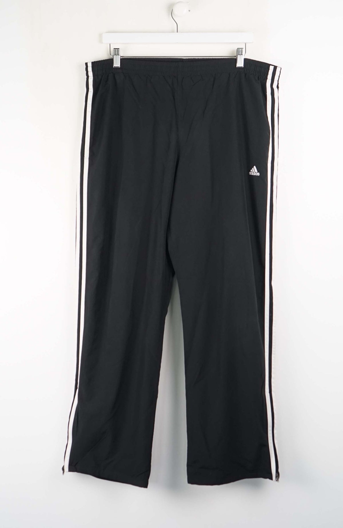 Black Adidas pants with white stripes on a white background