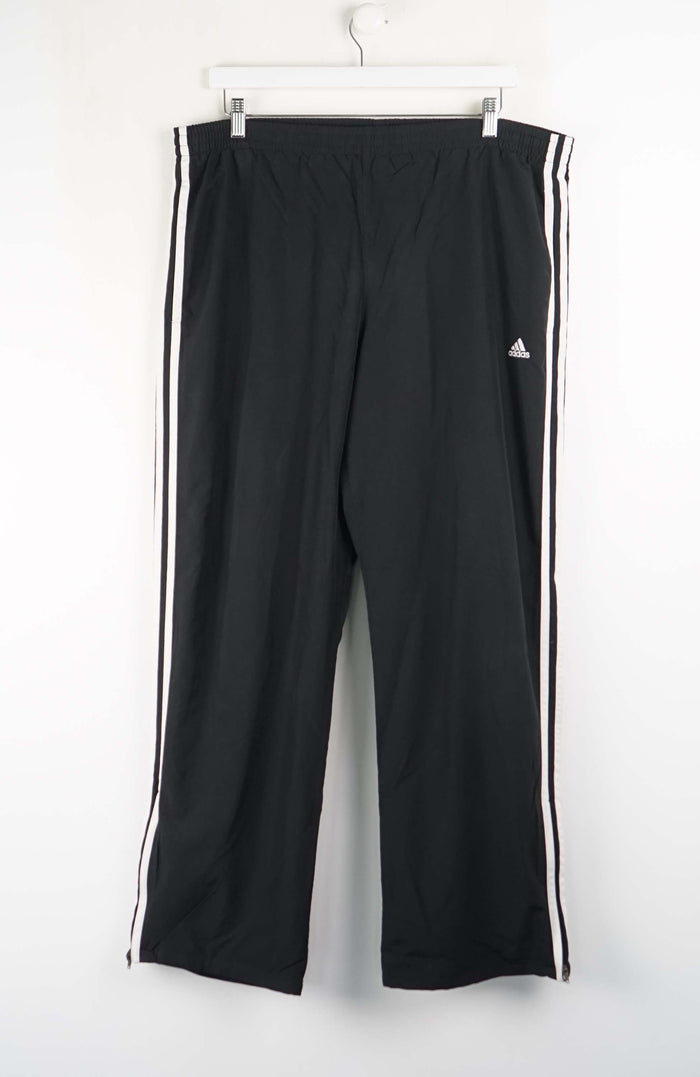 Black Adidas pants with white stripes on a white background