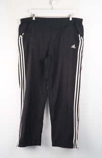 Black Adidas pants with white stripes on a white background