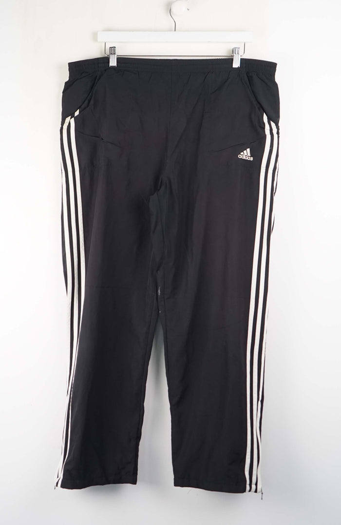 Black Adidas pants with white stripes on a white background