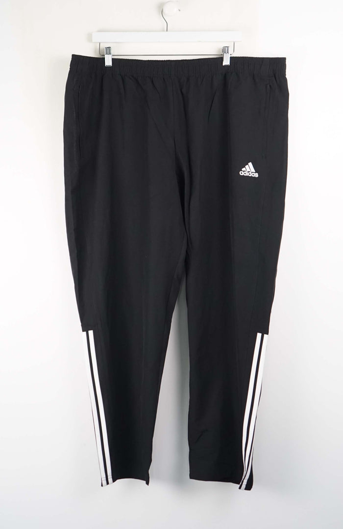 Black Adidas tracksuit pants with white stripes on a white background