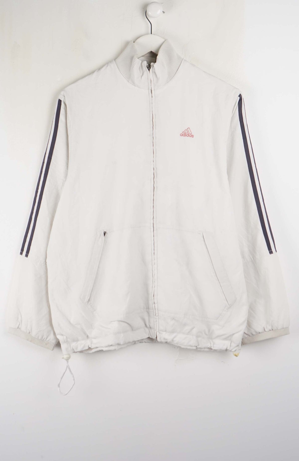 White jacket with black stripes on sleeves hanging on a white background