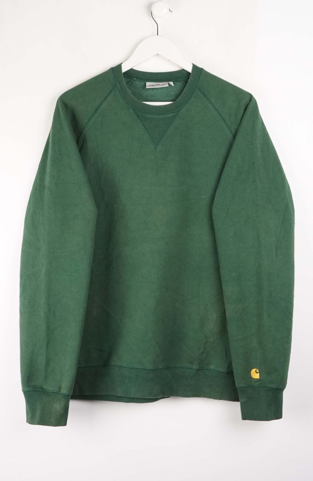 Green sweatshirt on a white hanger against a white background