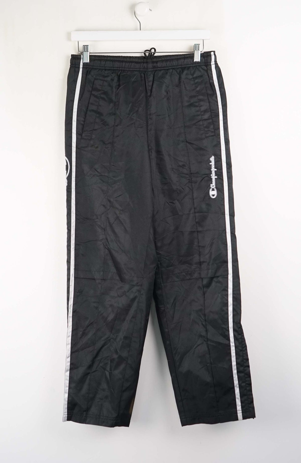 Black Champion track pants with white stripes on a white background