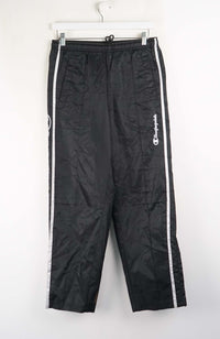 Black Champion track pants with white stripes on a white background