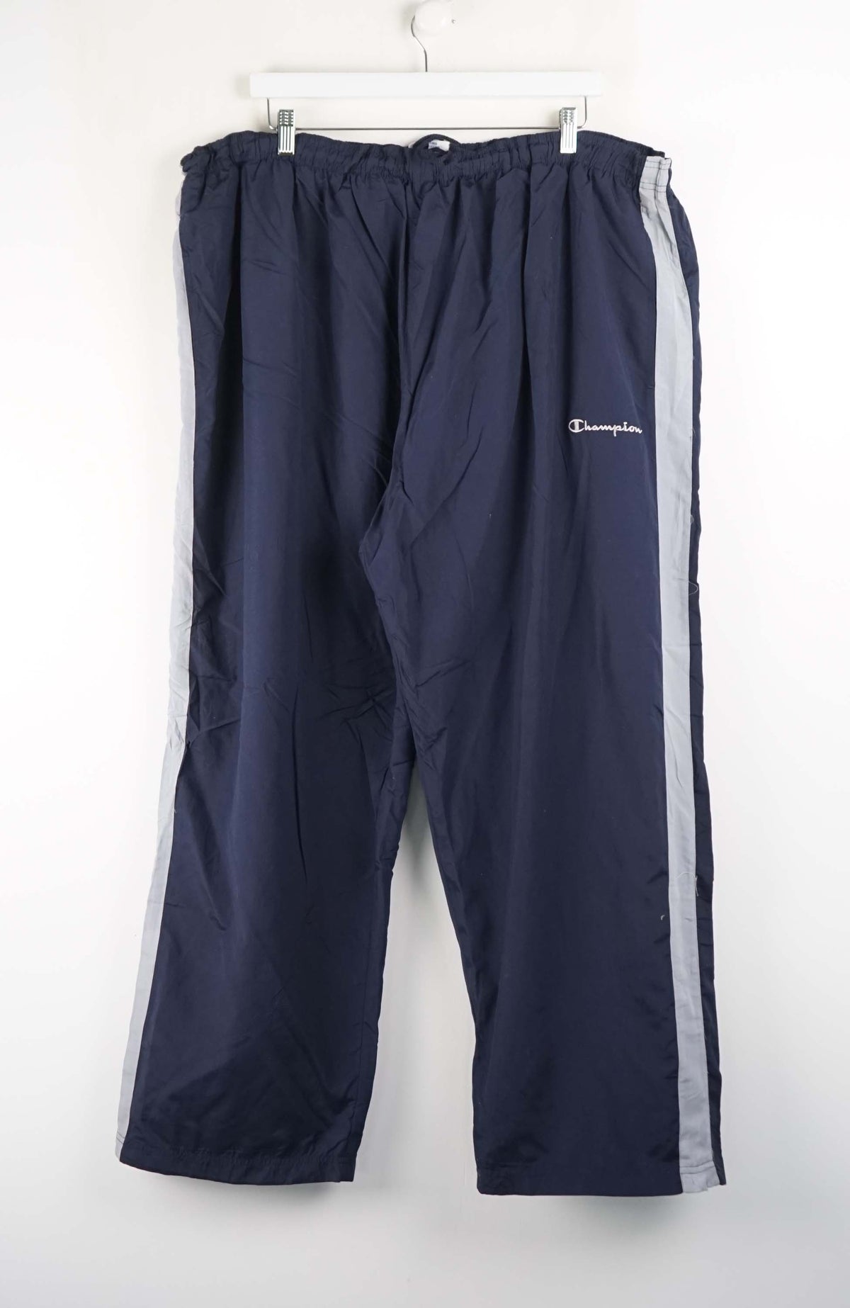 Navy blue track pants with a white stripe on a white background