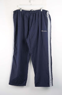 Navy blue track pants with a white stripe on a white background