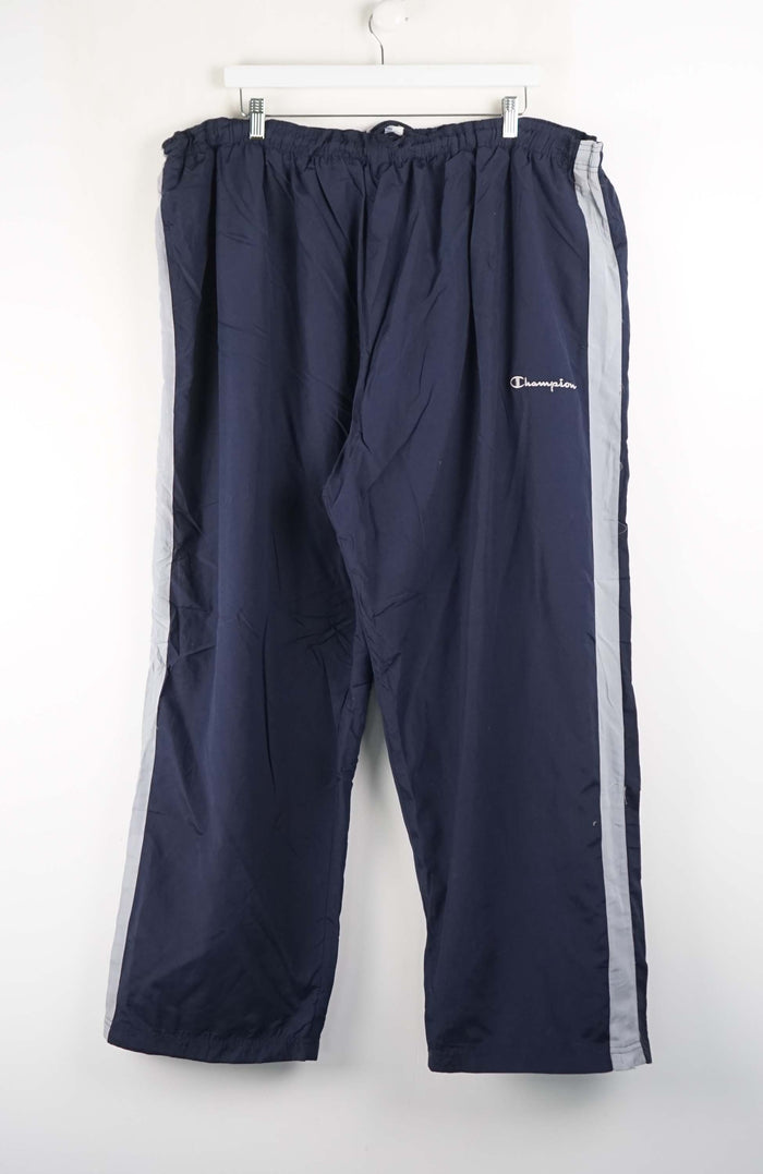 Navy blue track pants with a white stripe on a white background