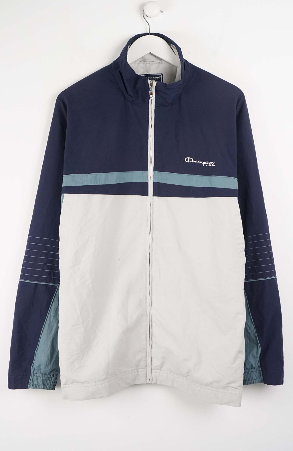 Navy and white jacket with Champion logo on a hanger against a white background