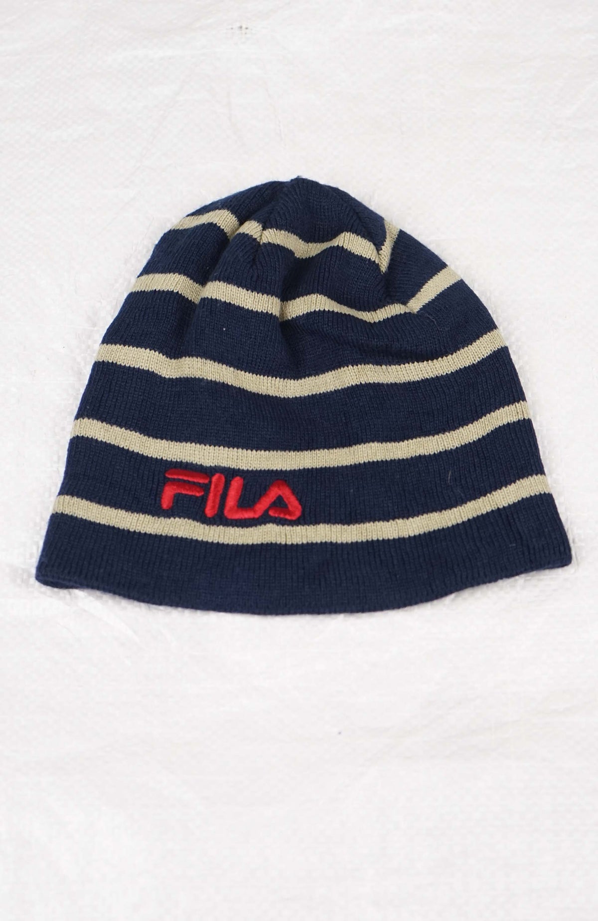 Navy and beige striped beanie with red FILA logo on a white background