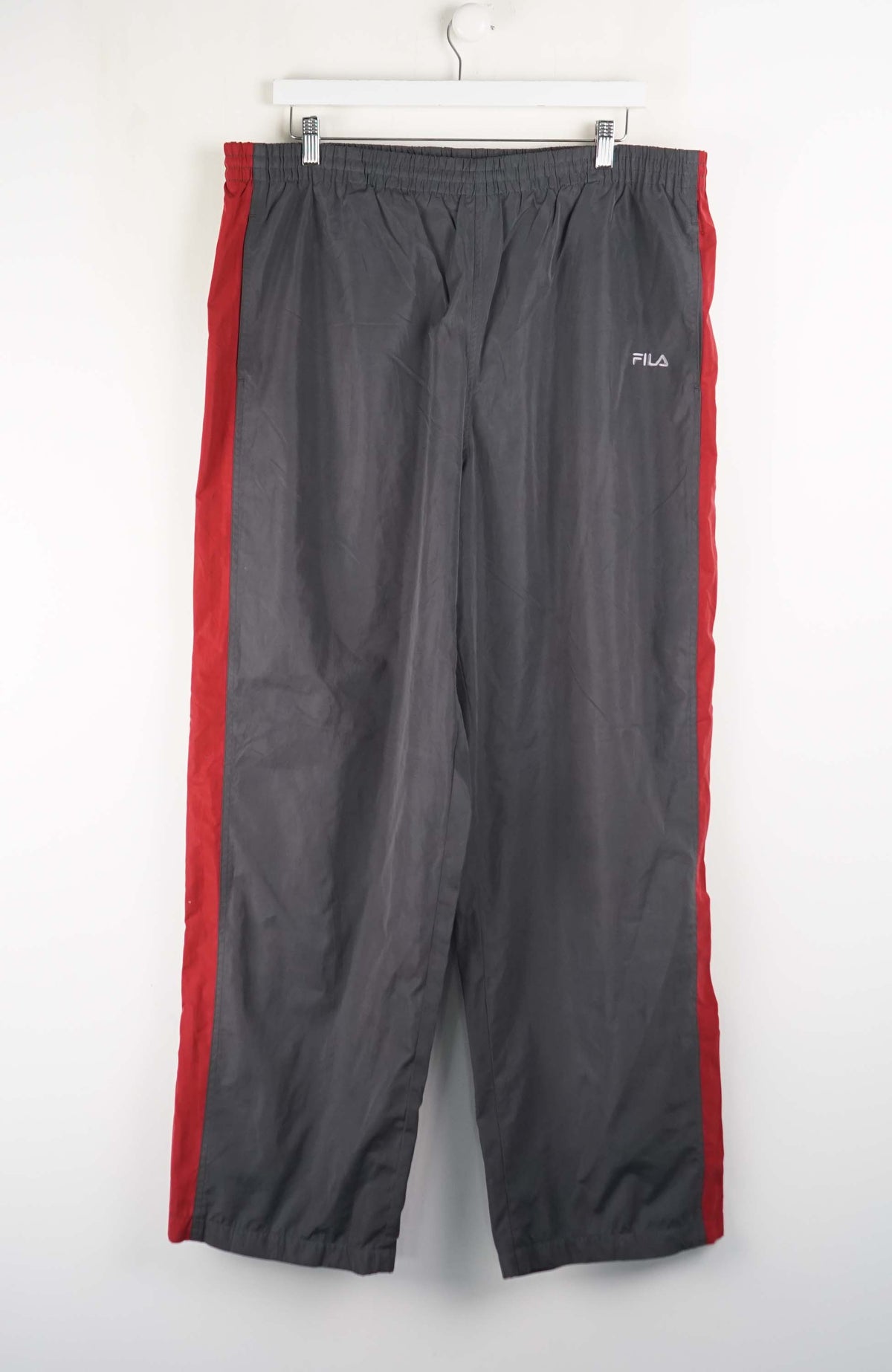 Gray pants with red accents hanging on a white wall