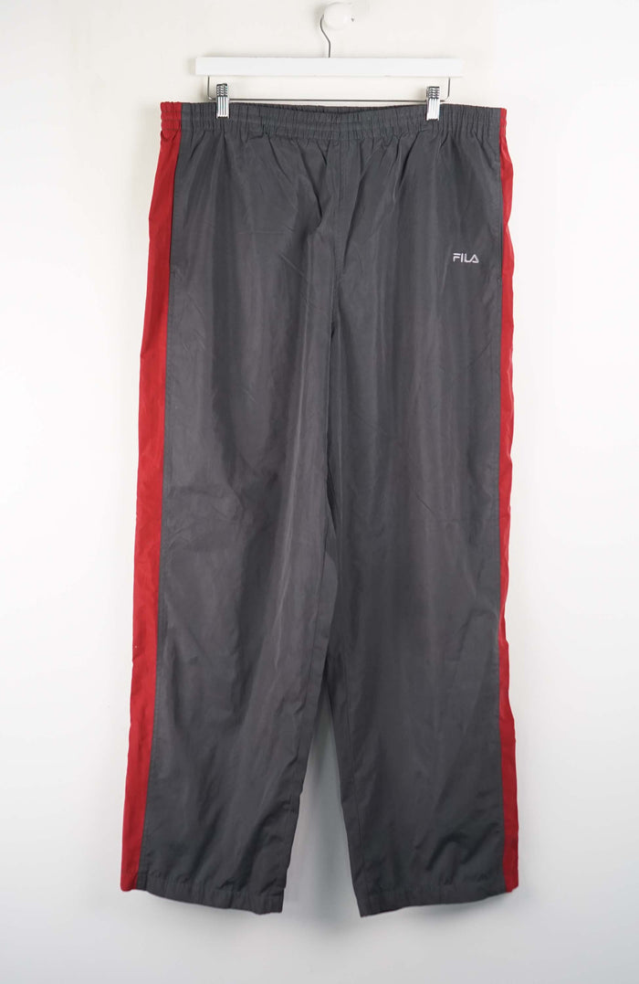 Gray pants with red accents hanging on a white wall