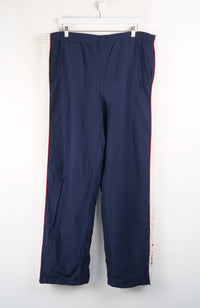 Navy blue pants with red trim hanging on a white background