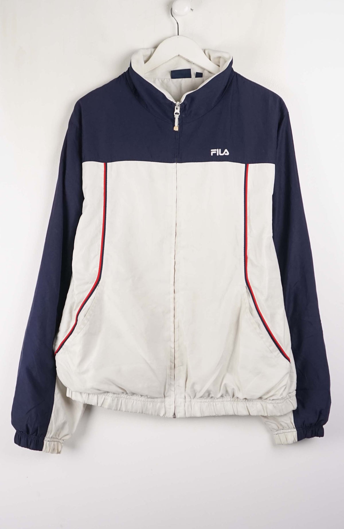 Navy and white jacket with red accents on a hanger against a white background