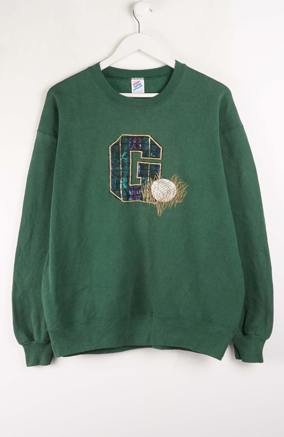 Green sweatshirt with a large letter 'G' and floral design on a white background