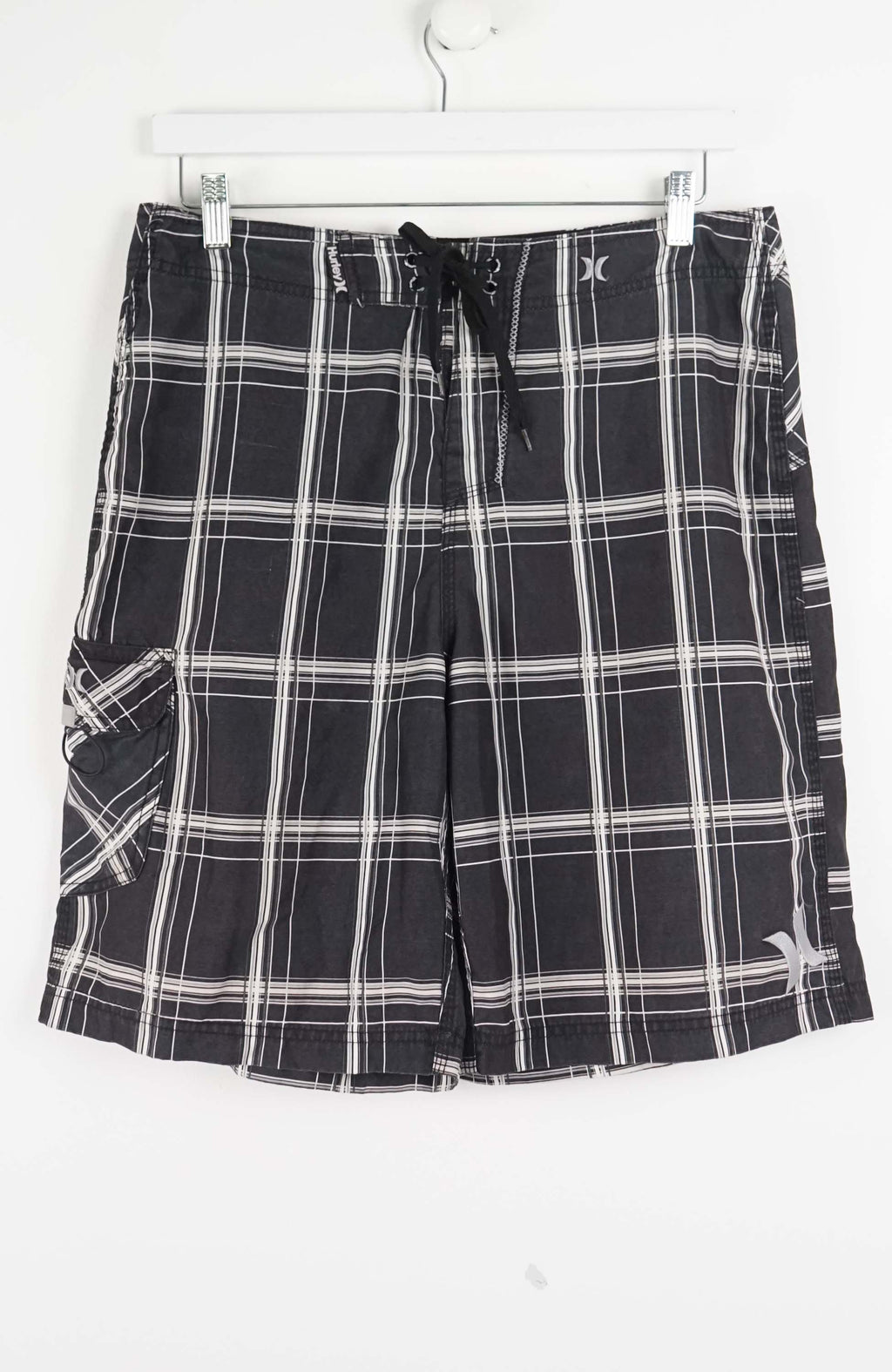 Black and white plaid shorts on a hanger against a white background