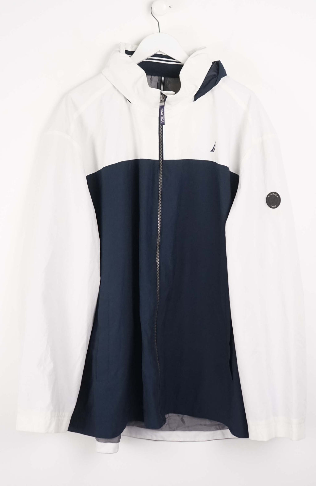 White and navy blue jacket on a hanger against a white background